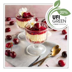 Dwa deserki w szklanych pucharkach z warstwą kremu waniliowego, na wierzchu z owocami wiśni i kwiatem. - AF70 8684