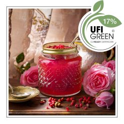 Słoik różowoczerwonego dżemu z łyżeczką w środku stoi na drewnianym stole - AF70 1447